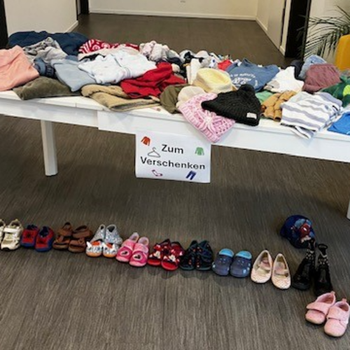 Ein Tisch voll mit Kinderkleidung und einem Schild „Zum Verschenken“